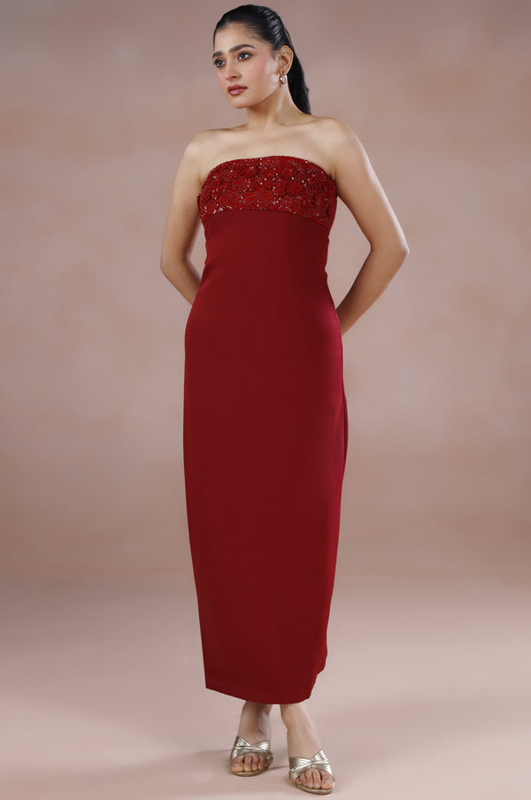 Woman wearing a strapless red dress against a plain background