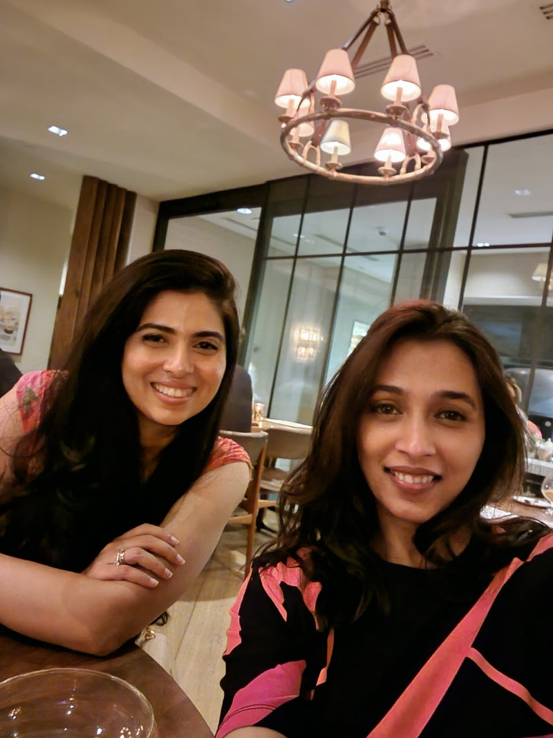 Two women posing for a photo indoors with a chandelier in the background.