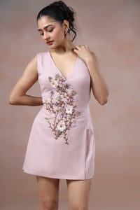Woman wearing a light pink dress with floral embroidery on a beige background