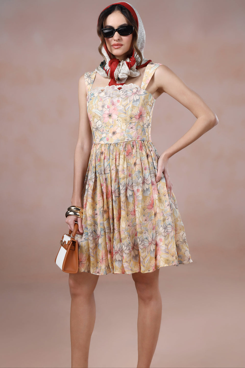 Woman wearing a floral dress with a headscarf and sunglasses on a beige background