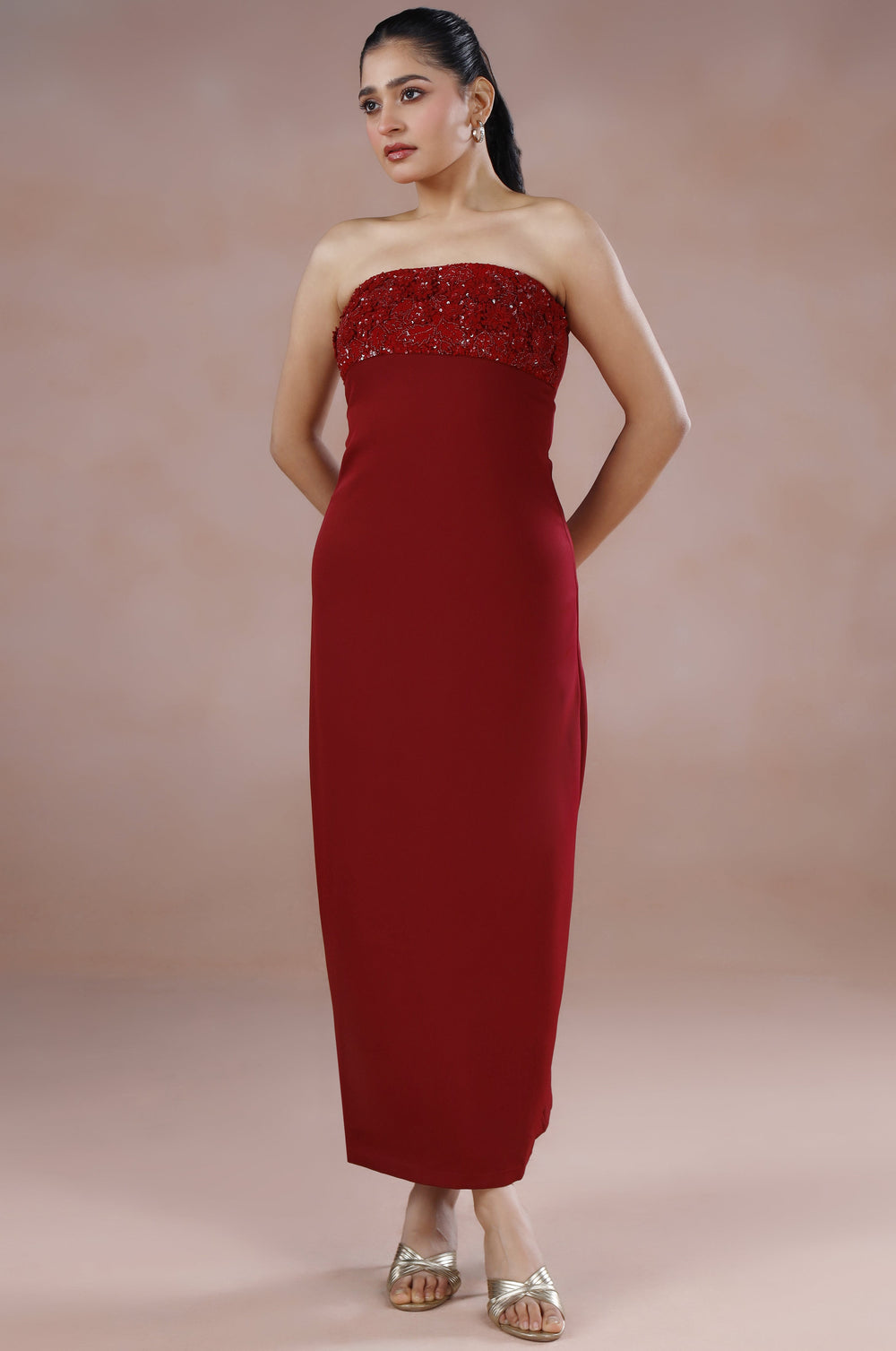 Woman wearing a strapless red dress against a plain background