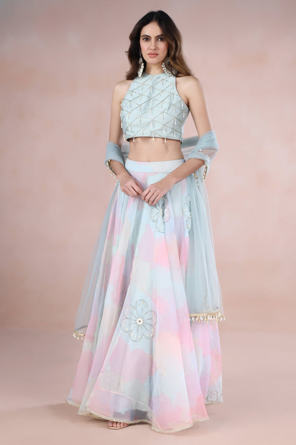 Woman wearing a pastel-colored traditional outfit with floral patterns on a pink background