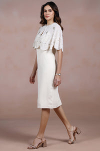 Woman wearing a white dress with a lace top against a beige background