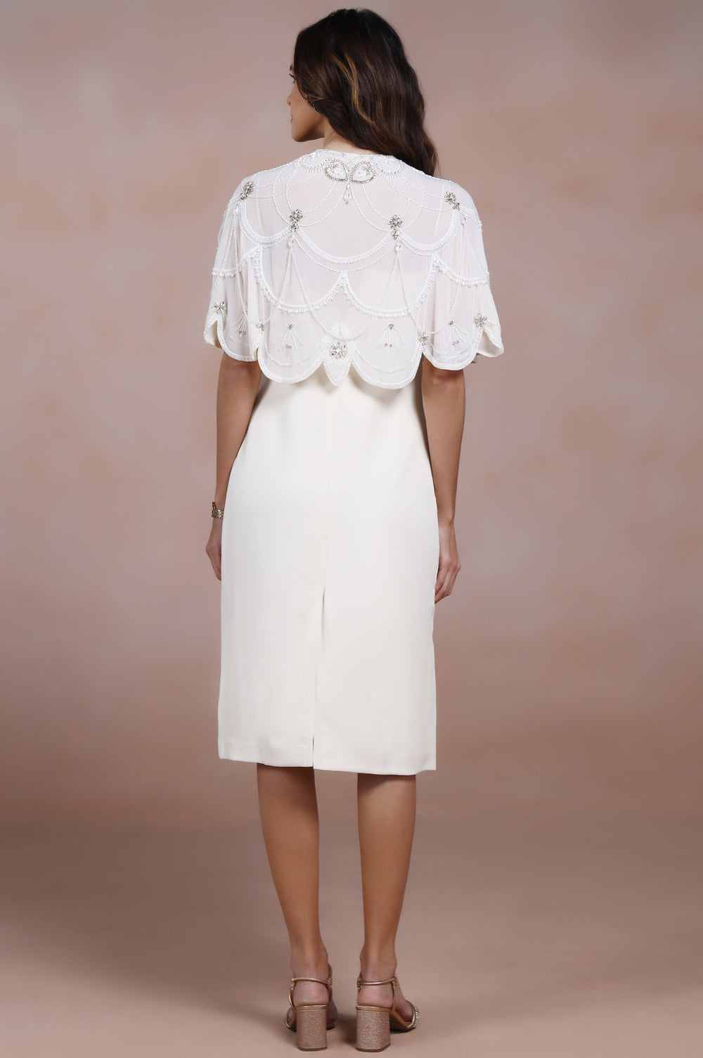 Woman wearing a white dress with lace details on a beige background