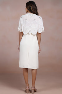 Woman wearing a white dress with lace details on a beige background
