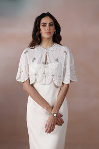 Woman wearing a white lace top and skirt against a plain background