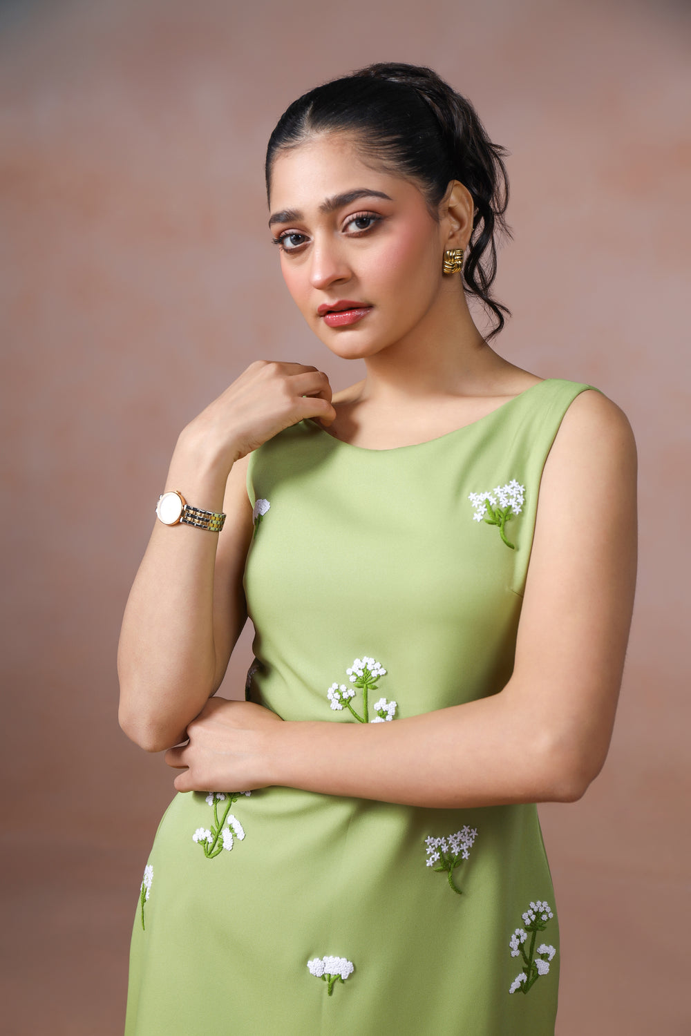 Woman wearing a green dress with floral patterns against a brown background