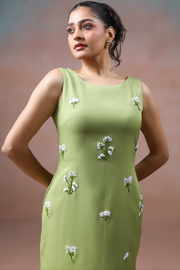 Woman wearing a green dress with floral patterns against a blurred background