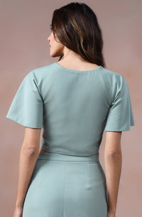 Woman wearing a light blue dress against a pinkish-beige background