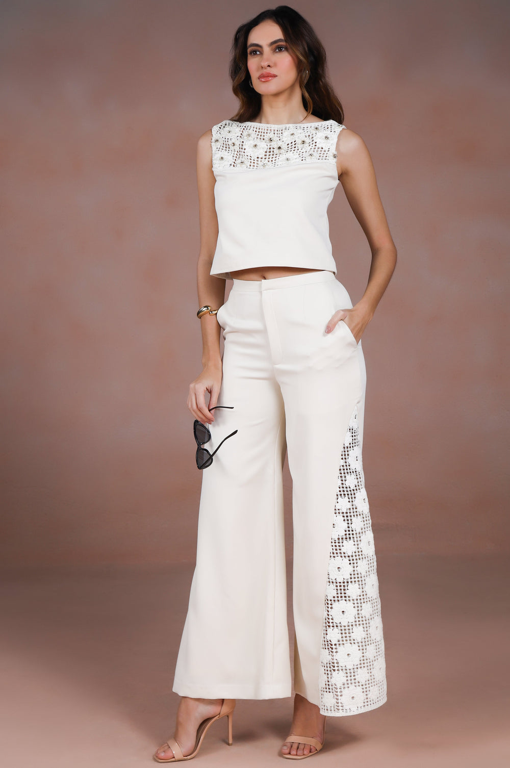 Woman wearing a white outfit with floral details against a brown background