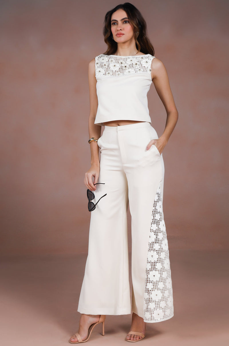 Woman wearing a white outfit with floral details against a brown background