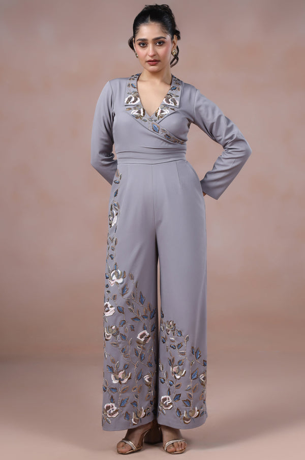 Woman wearing a gray jumpsuit with floral patterns on a beige background