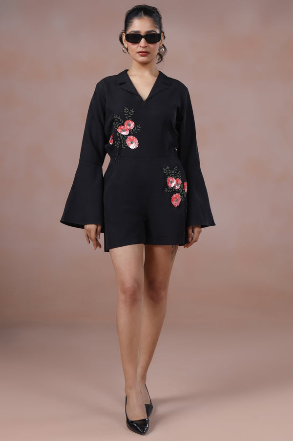 Woman wearing a black dress with floral embroidery on a beige background