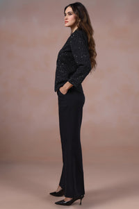 Woman in a black outfit standing against a beige background