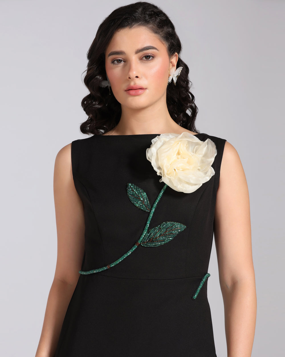 Woman wearing a black dress with a white floral design on a gray background